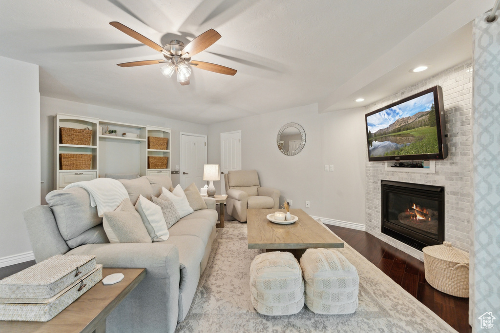 Living area with wood finished floors, baseboards, ceiling fan, a brick fireplace, and recessed lighting
