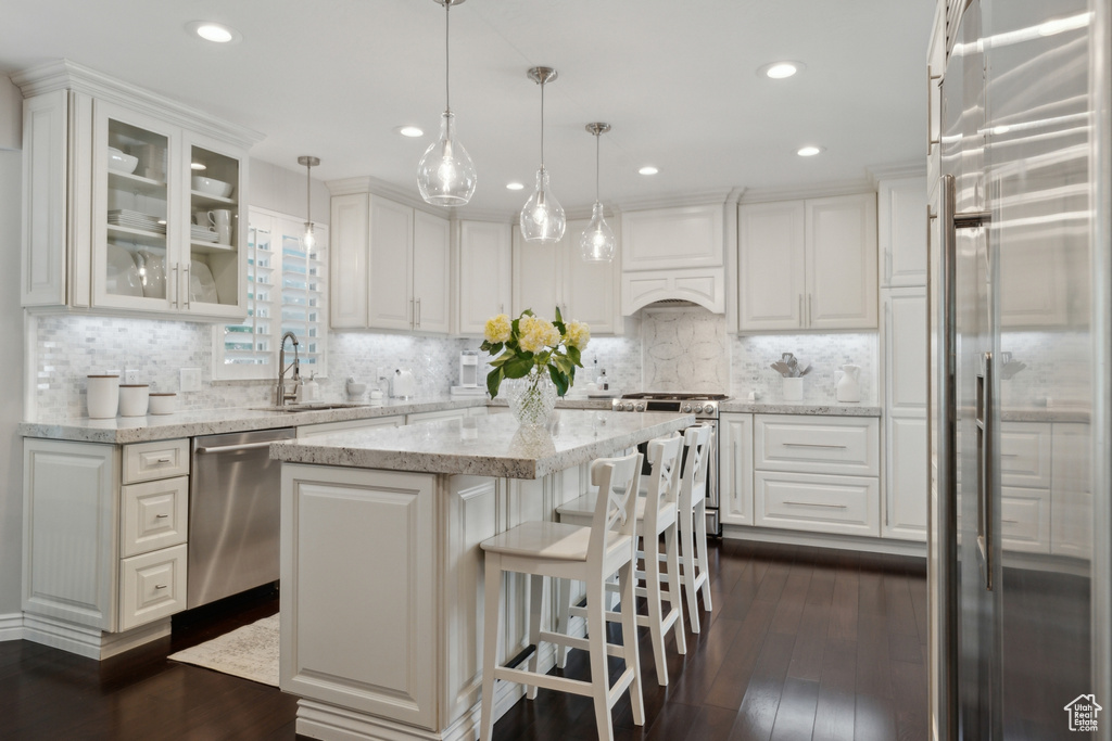 Kitchen with stainless steel appliances, a sink, white cabinetry, dark wood-style floors, and a kitchen island