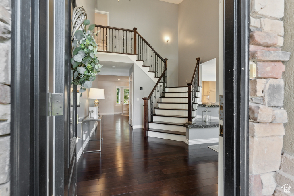 Entryway with dark wood finished floors, stairway, a high ceiling, and baseboards