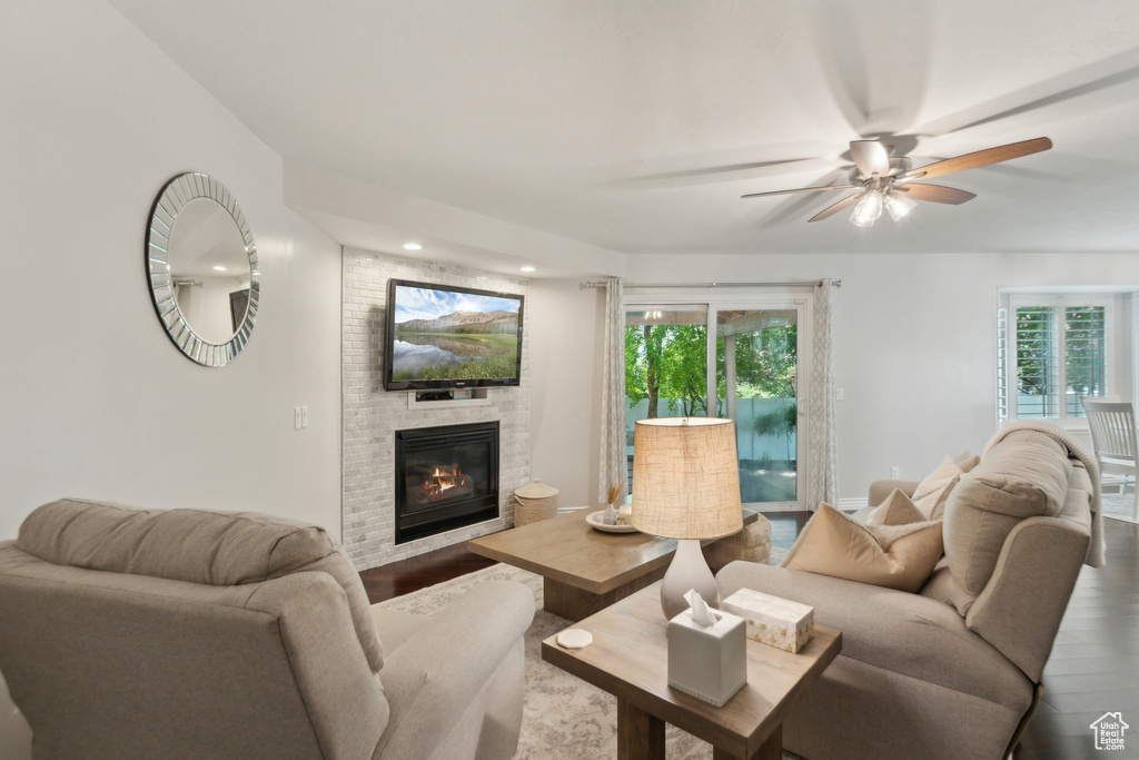 Living room featuring wood finished floors, ceiling fan, a large fireplace, and recessed lighting