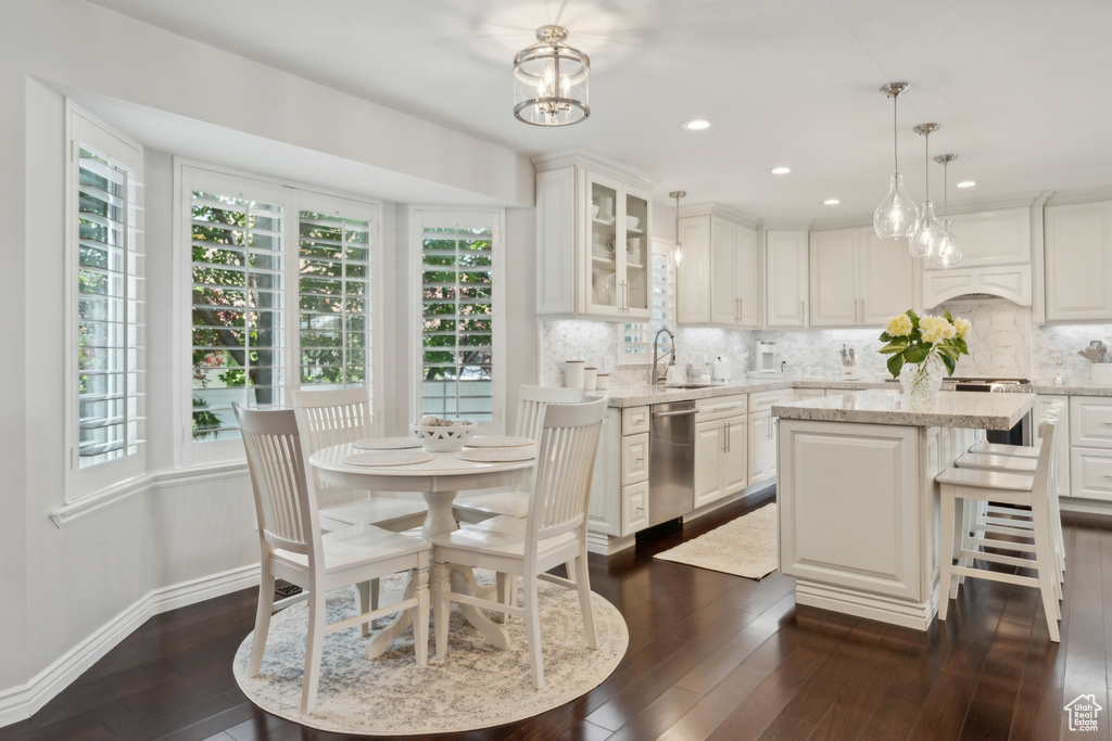 Dining area with dark wood-style flooring, baseboards, recessed lighting, and a chandelier