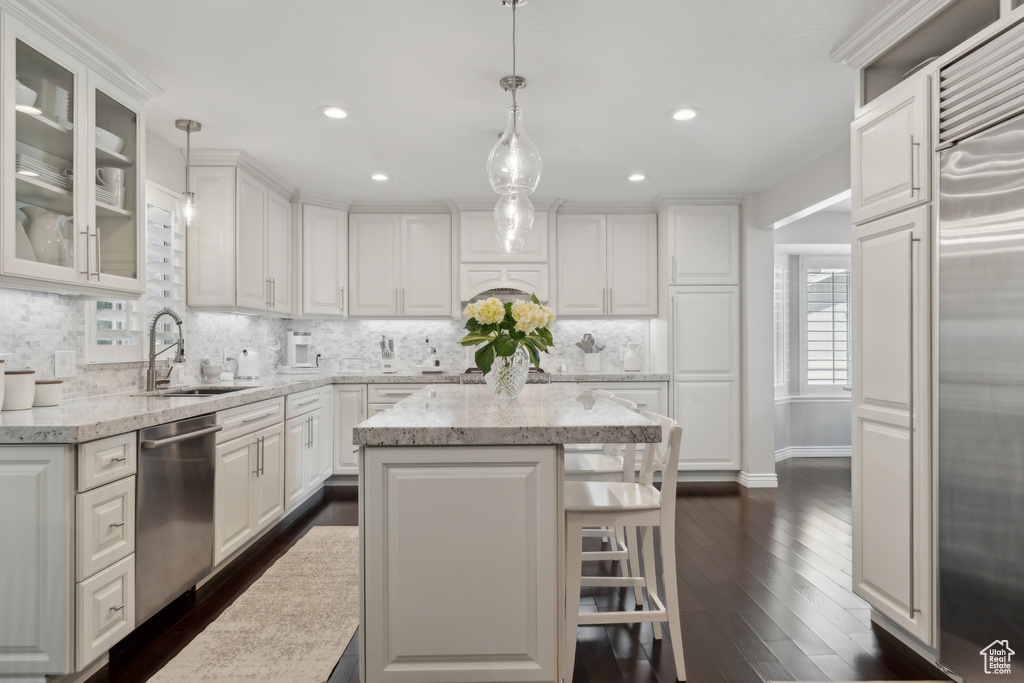 Kitchen featuring appliances with stainless steel finishes, a sink, tasteful backsplash, white cabinetry, and dark wood finished floors
