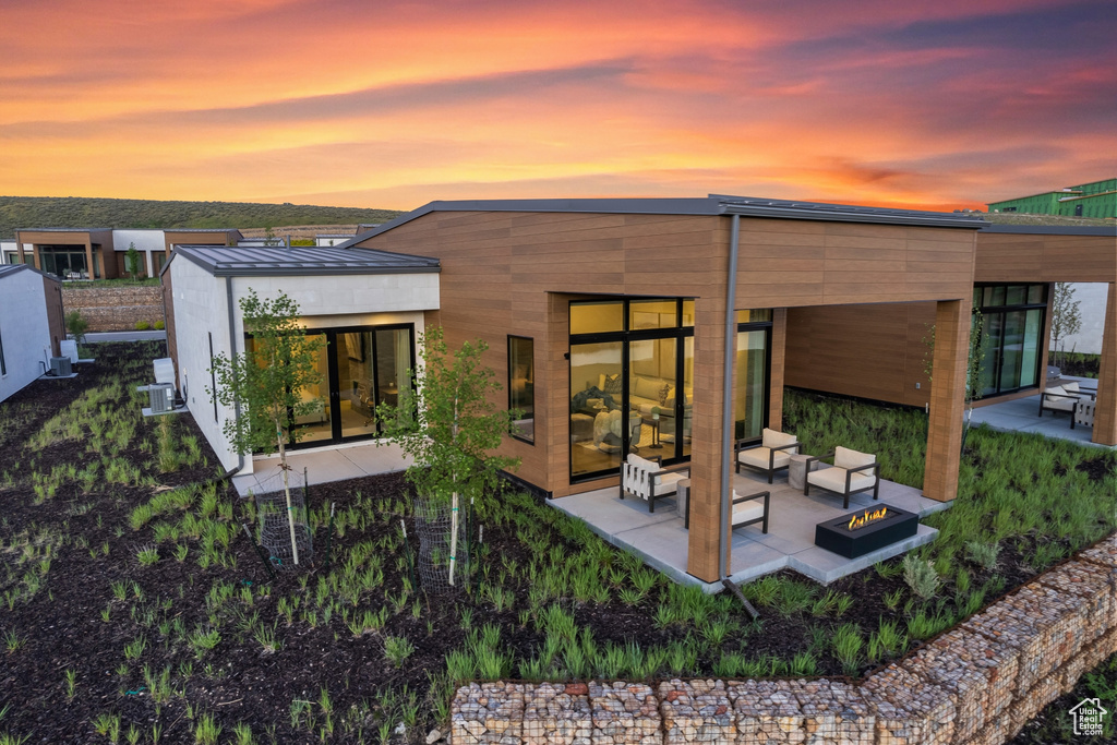 Back of house with a fire pit, a patio area, metal roof, and a standing seam roof