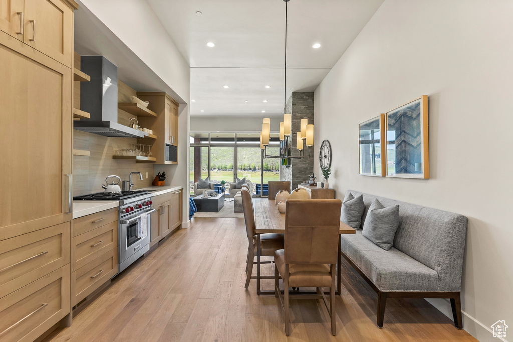 Kitchen featuring designer stove, open floor plan, wall chimney exhaust hood, recessed lighting, and open shelves