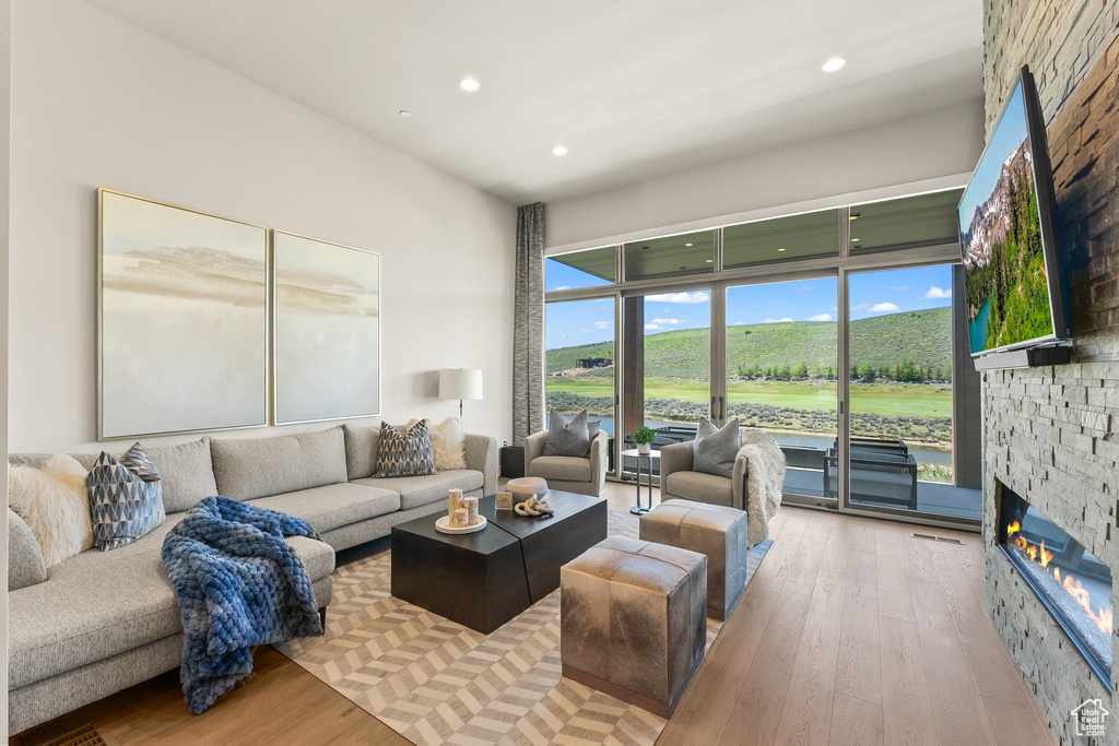 Living room featuring hardwood / wood-style flooring, a stone fireplace, and recessed lighting