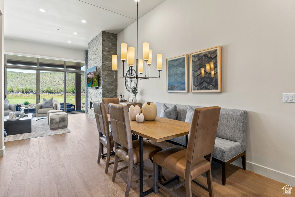 Dining area featuring wood finished floors, a chandelier, a high ceiling, baseboards, and recessed lighting
