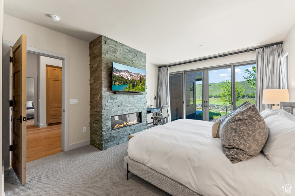 Carpeted bedroom with access to outside and a stone fireplace
