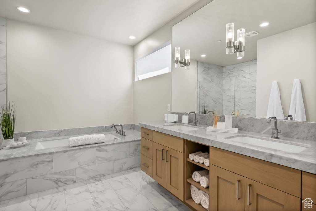 Full bath featuring double vanity, a bath, marble finish floors, and recessed lighting