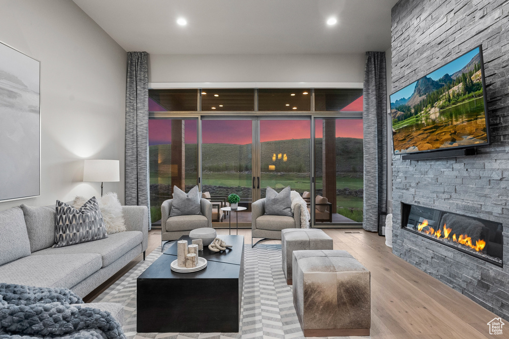 Living room featuring wood finished floors, a stone fireplace, and recessed lighting