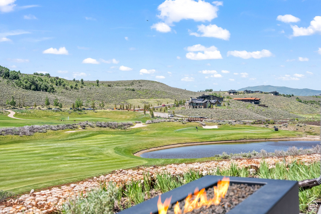 View of property's community with an outdoor fire pit, a water and mountain view, and view of golf course
