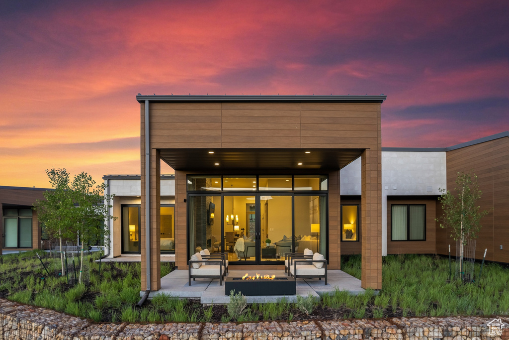 Back of property with a patio area and an outdoor living space with a fire pit
