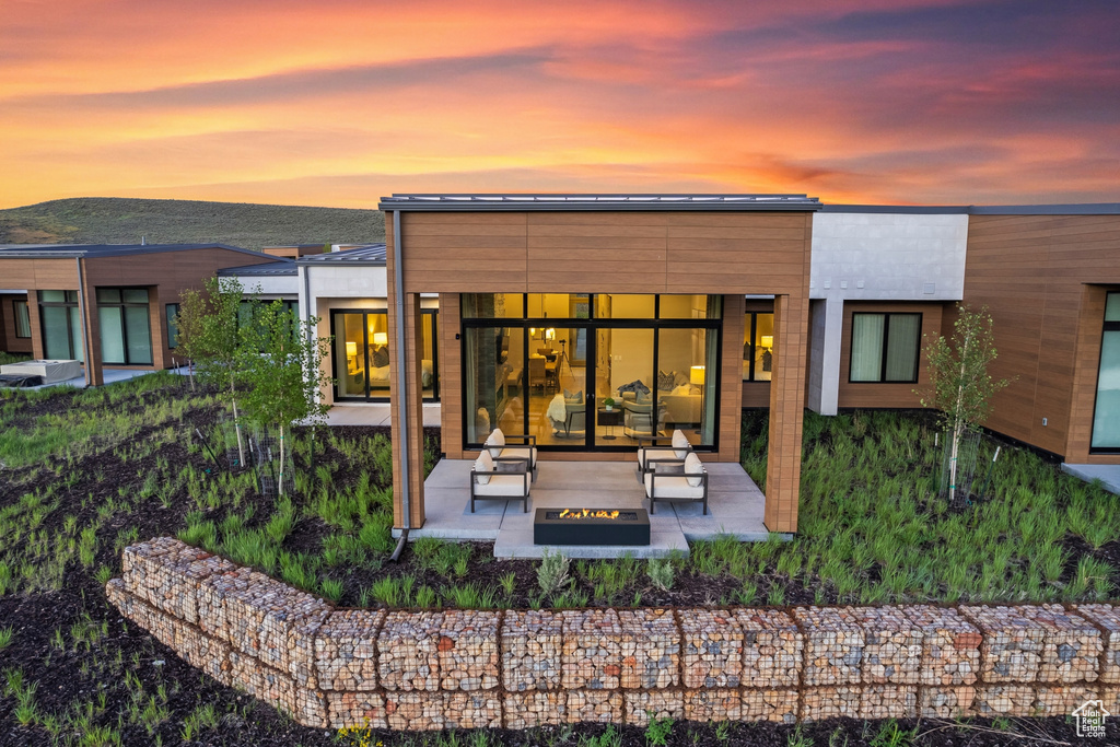 Back of property at dusk featuring a fire pit, a patio area, and a mountain view
