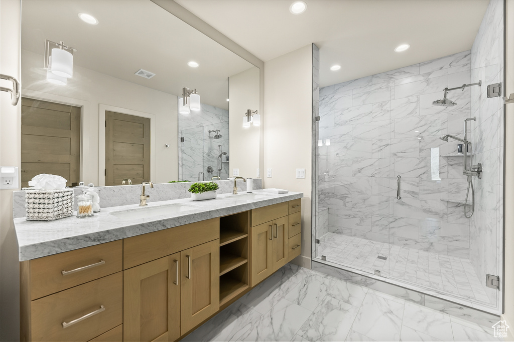 Bathroom featuring double vanity, marble look tiles, recessed lighting, and a marble finish shower