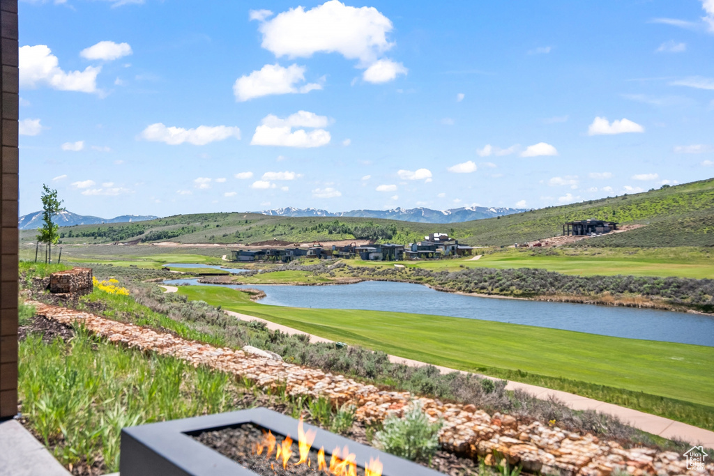 View of property's community with view of golf course, a water and mountain view, and a fire pit