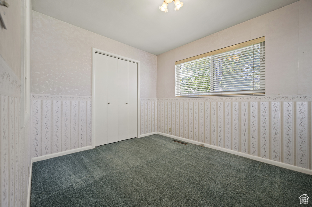 Unfurnished bedroom featuring carpet flooring, wallpapered walls, and a closet