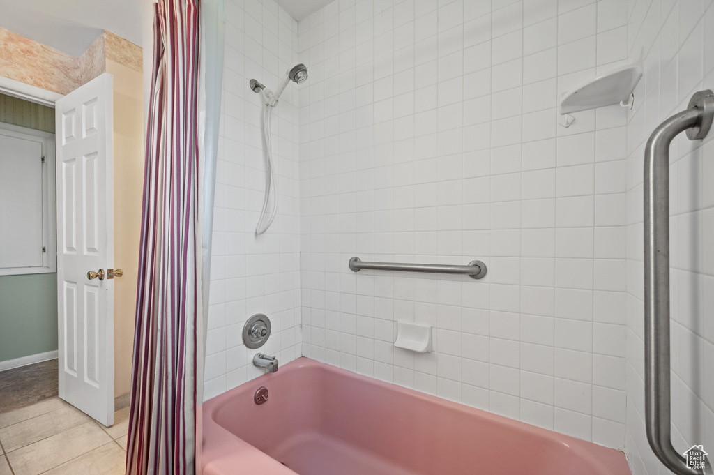 Full bathroom with shower / tub combo with curtain, tile patterned flooring, and baseboards