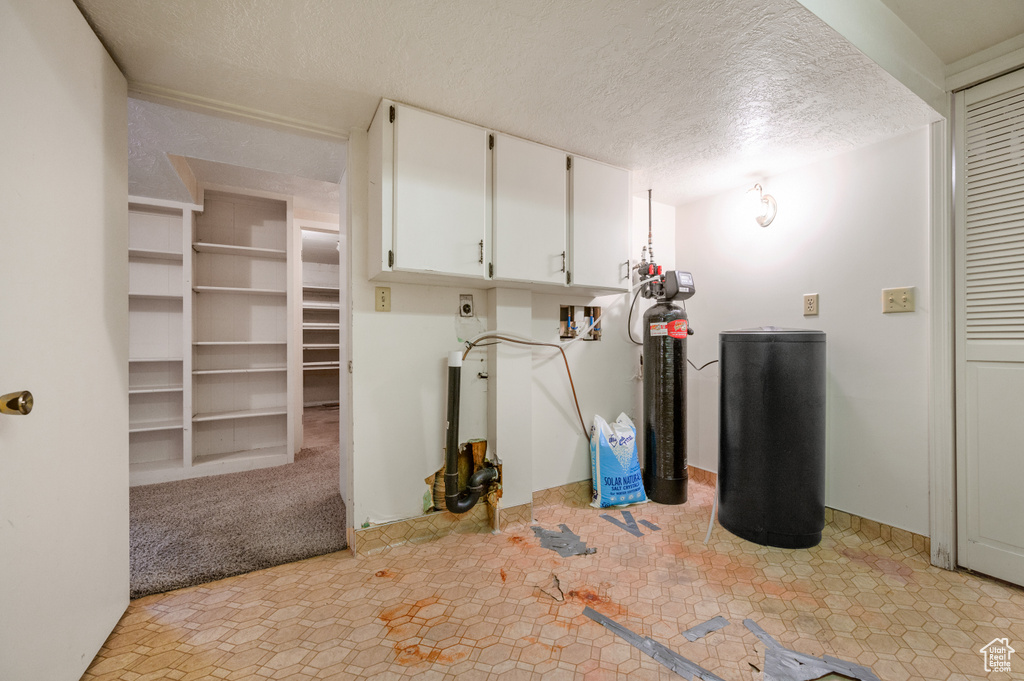 Finished basement with a textured ceiling and a water softener system