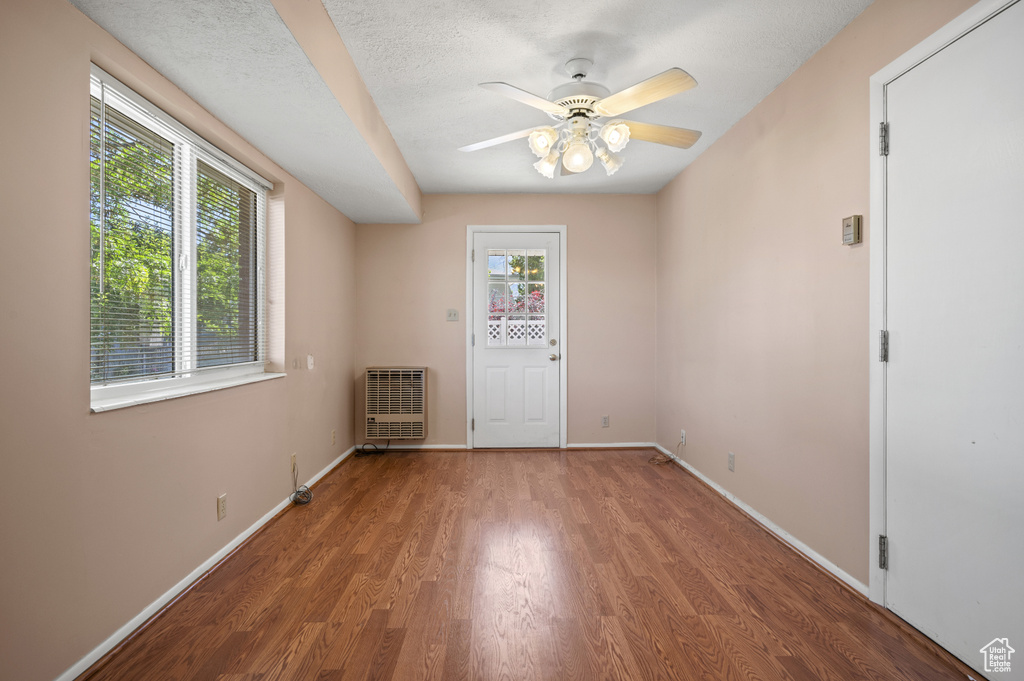 Empty room with heating unit, wood finished floors, baseboards, and a ceiling fan
