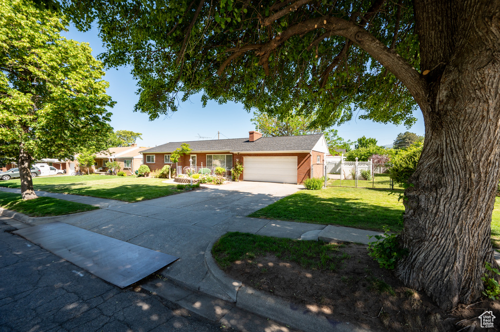 Ranch-style home featuring a garage, driveway, brick siding, and a chimney