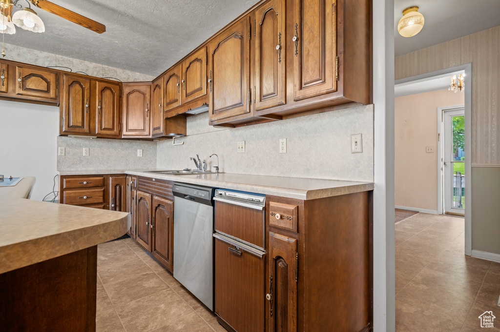 Kitchen featuring dishwasher, brown cabinets, light tile patterned floors, decorative backsplash, and a sink