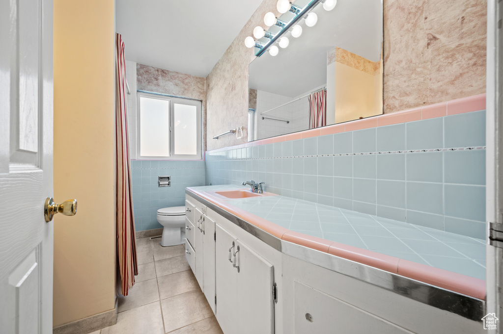 Full bathroom featuring tile patterned floors, tile walls, vanity, toilet, and a shower with shower curtain