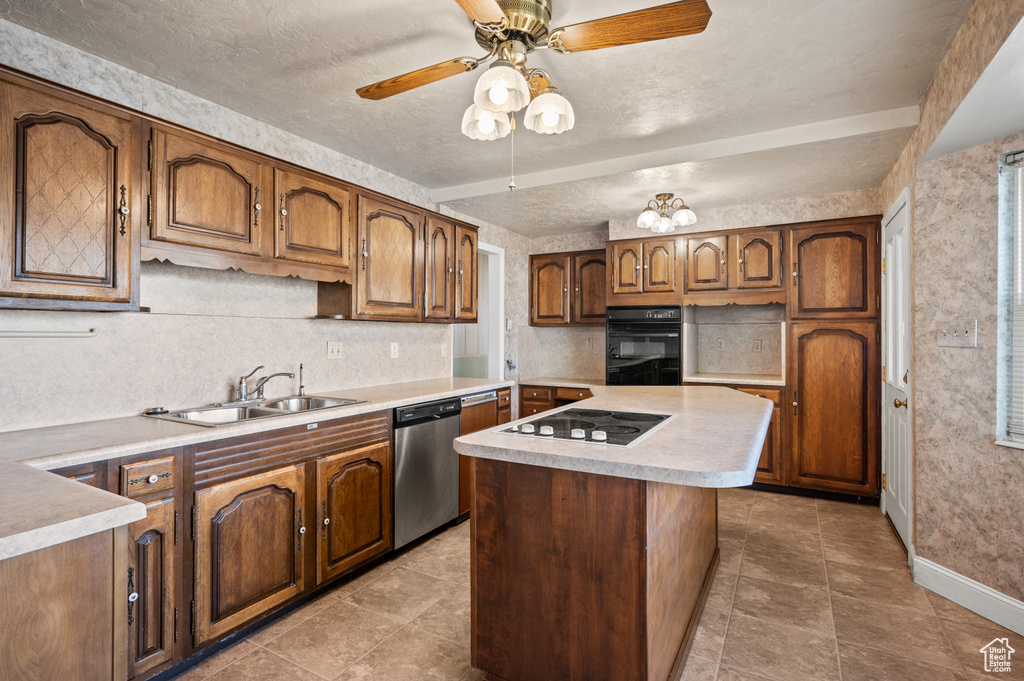 Kitchen with black appliances, a sink, light countertops, baseboards, and a textured ceiling