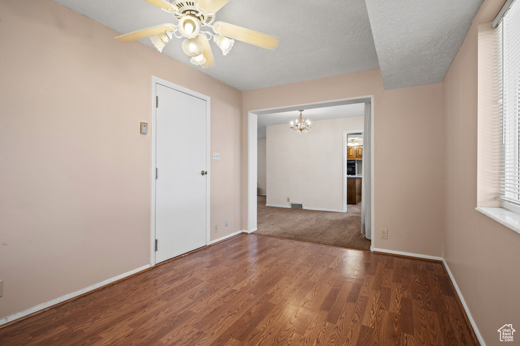 Unfurnished room featuring a chandelier, baseboards, wood finished floors, and ceiling fan