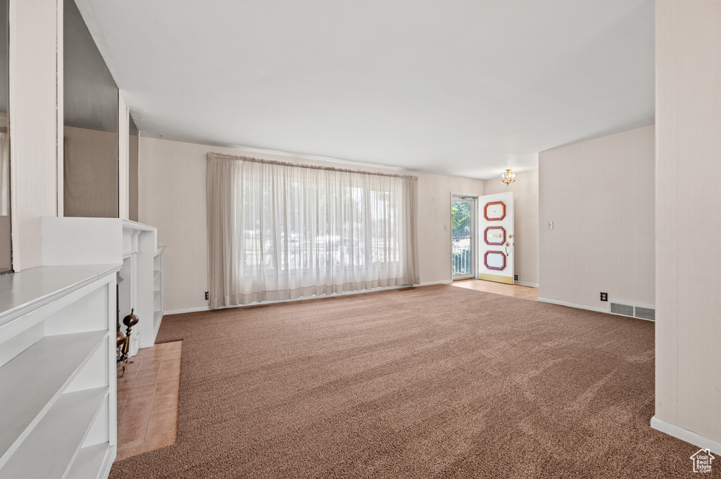 Unfurnished living room featuring carpet and baseboards