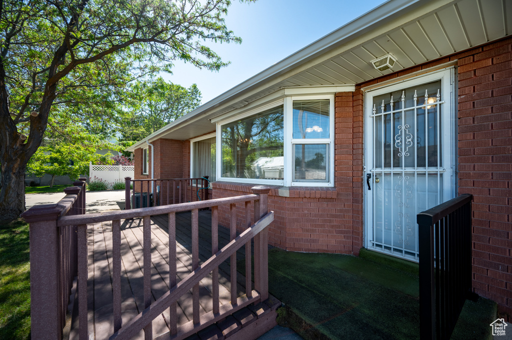 View of exterior entry with brick siding and a deck
