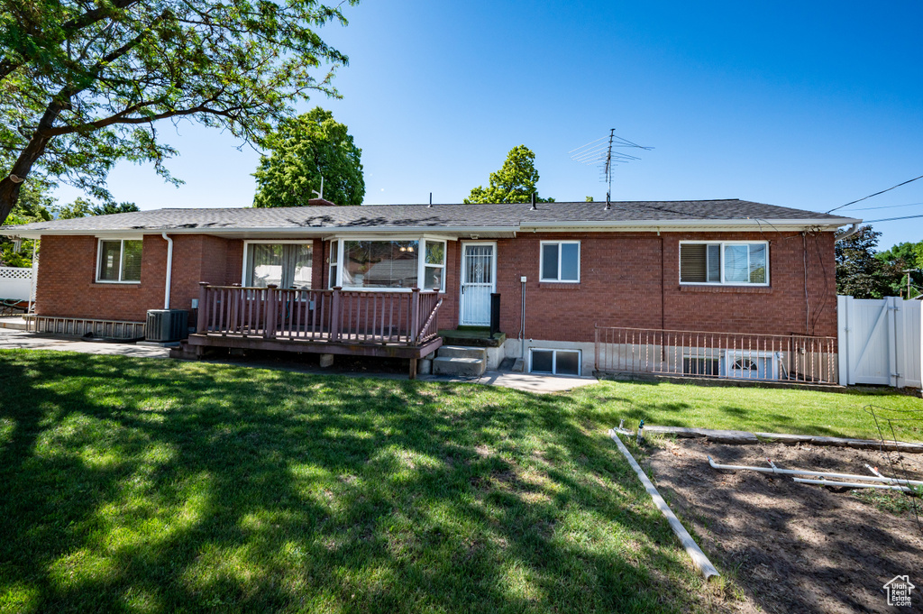 Back of property with brick siding, a deck, and central AC unit