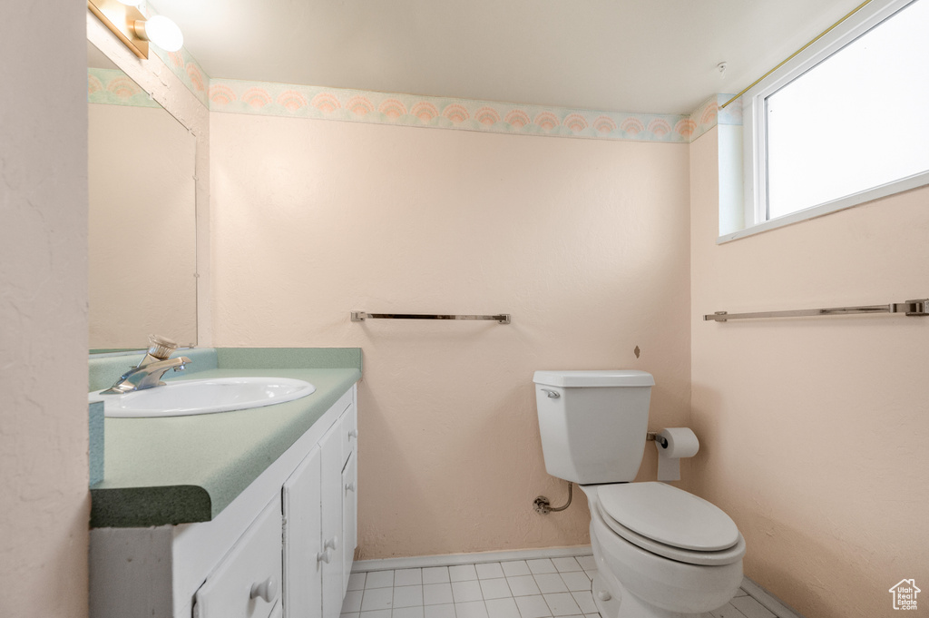 Half bath with toilet, vanity, baseboards, and tile patterned floors