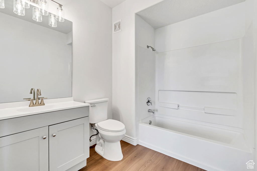 Bathroom featuring vanity, toilet, shower / bath combination, and wood finished floors