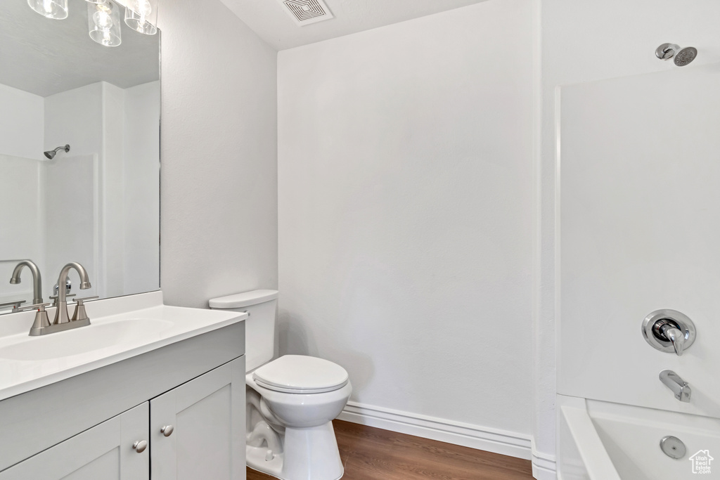 Bathroom featuring vanity, wood finished floors, shower / bath combination, and toilet