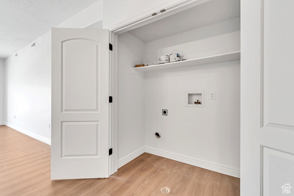 Laundry area featuring hookup for an electric dryer, washer hookup, light wood-style floors, and baseboards
