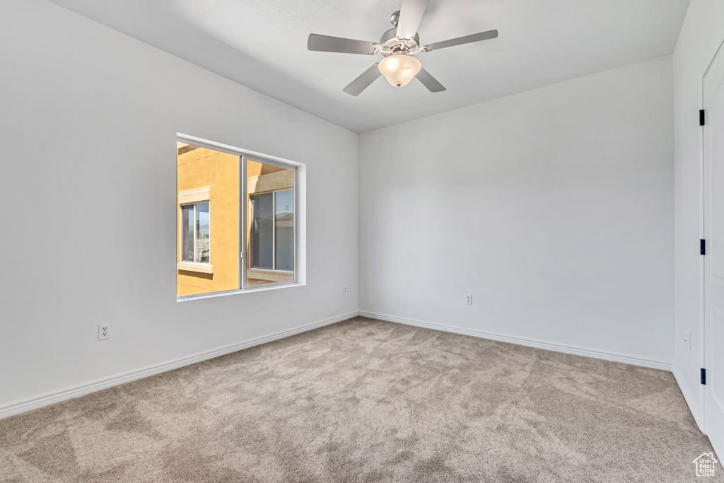 Spare room with carpet floors, a ceiling fan, and baseboards