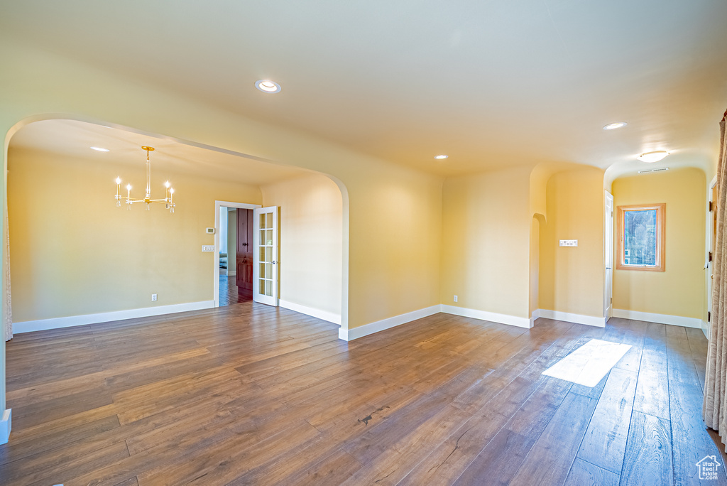 Spare room with arched walkways, a chandelier, dark wood-style flooring, recessed lighting, and baseboards