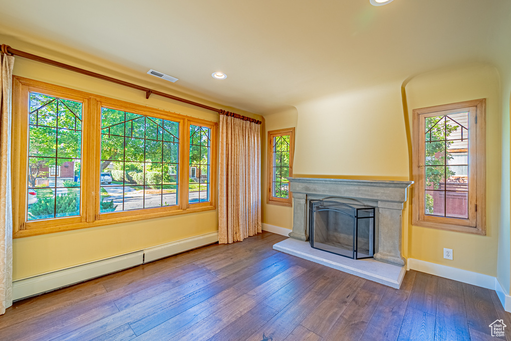 Unfurnished living room featuring baseboard heating, baseboards, a high end fireplace, hardwood / wood-style floors, and recessed lighting