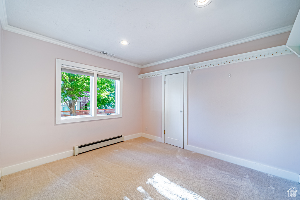 Unfurnished bedroom featuring baseboard heating, ornamental molding, baseboards, light carpet, and recessed lighting