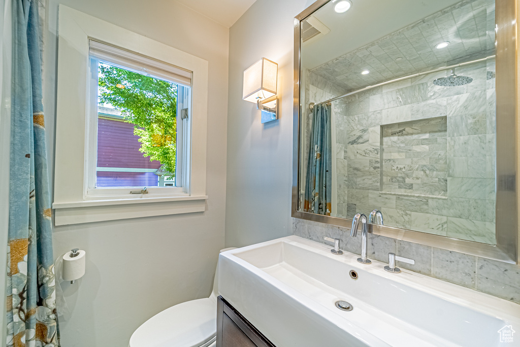 Bathroom featuring vanity, tiled shower, and toilet