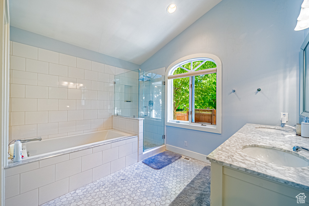 Full bath featuring a stall shower, vaulted ceiling, a garden tub, double vanity, and tile patterned floors