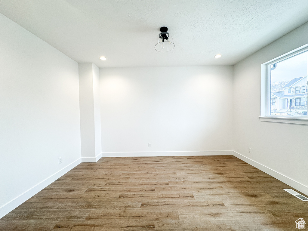 Empty room with wood finished floors, recessed lighting, and baseboards