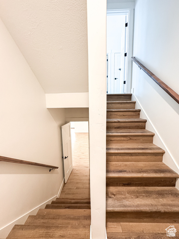 Stairway featuring wood finished floors