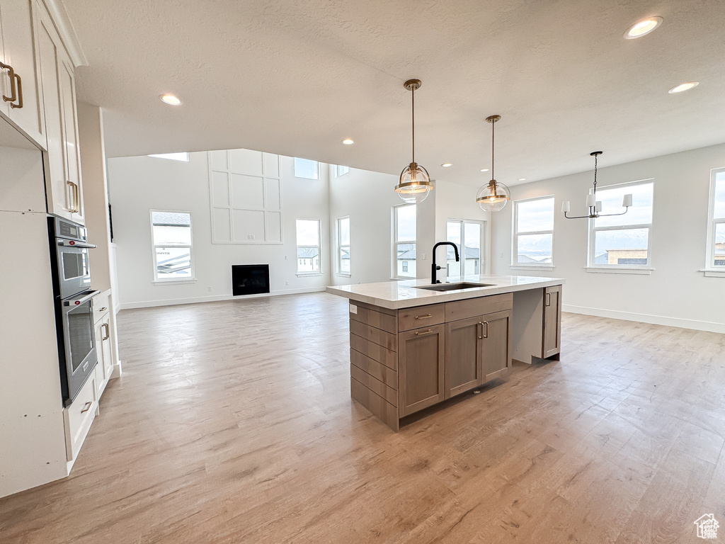 Kitchen featuring a sink, open floor plan, recessed lighting, baseboards, and light countertops