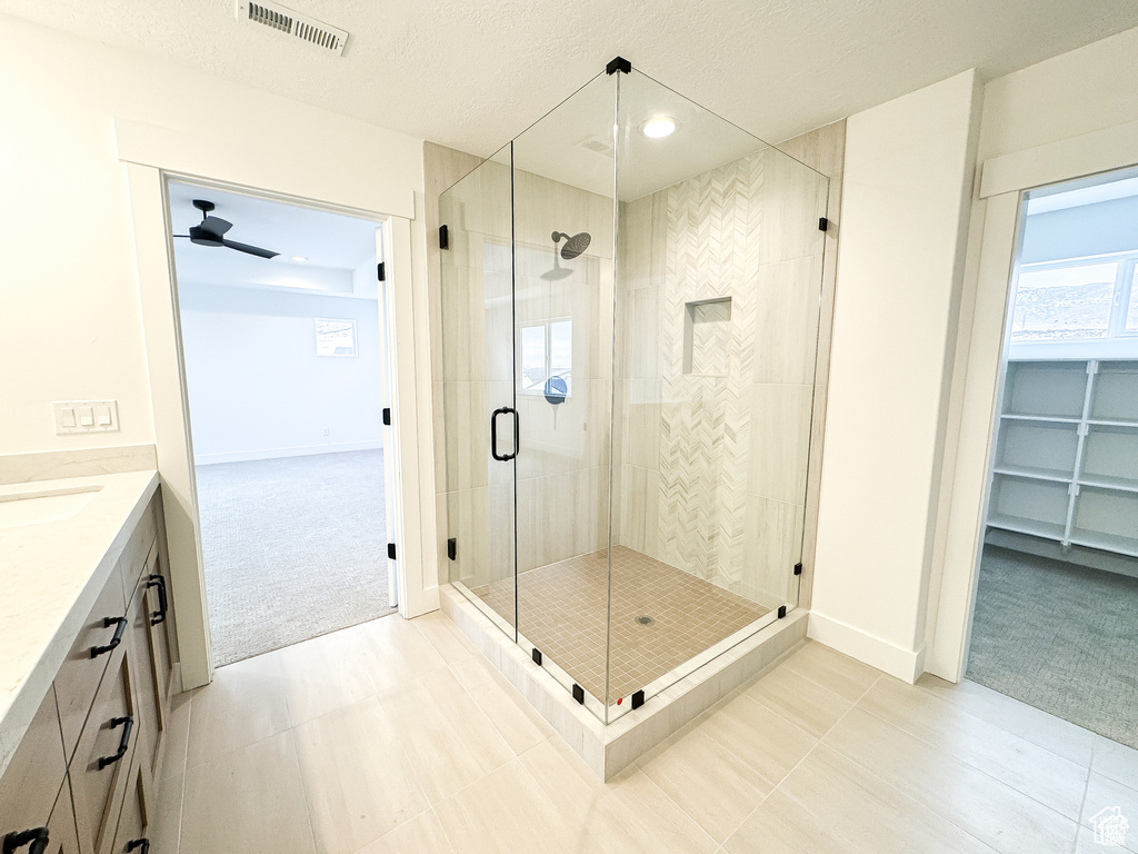Full bathroom featuring a shower stall, vanity, baseboards, and a ceiling fan
