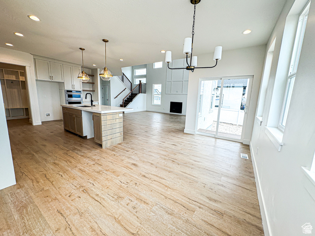 Kitchen with baseboards, open floor plan, a sink, recessed lighting, and light wood-type flooring