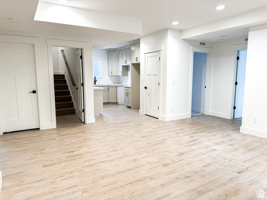 Unfurnished living room with light wood-type flooring, stairway, baseboards, and recessed lighting