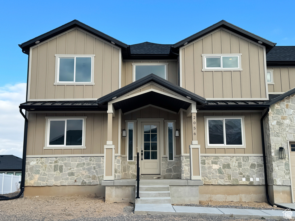 View of front of property with stone siding, a standing seam roof, metal roof, and a shingled roof