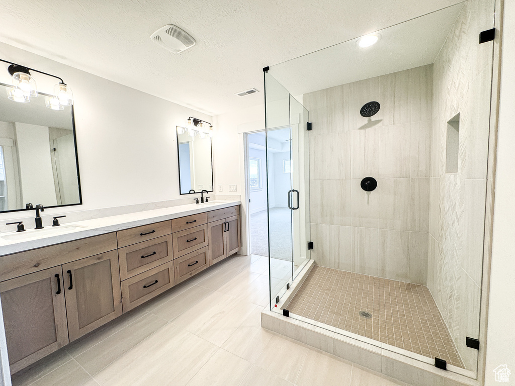 Bathroom featuring a shower stall, double vanity, and tile patterned flooring