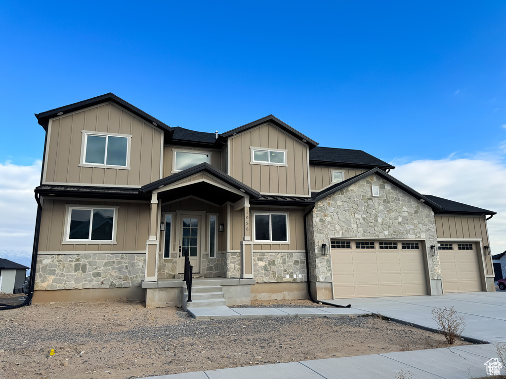 View of front of home featuring stone siding, a garage, driveway, and board and batten siding