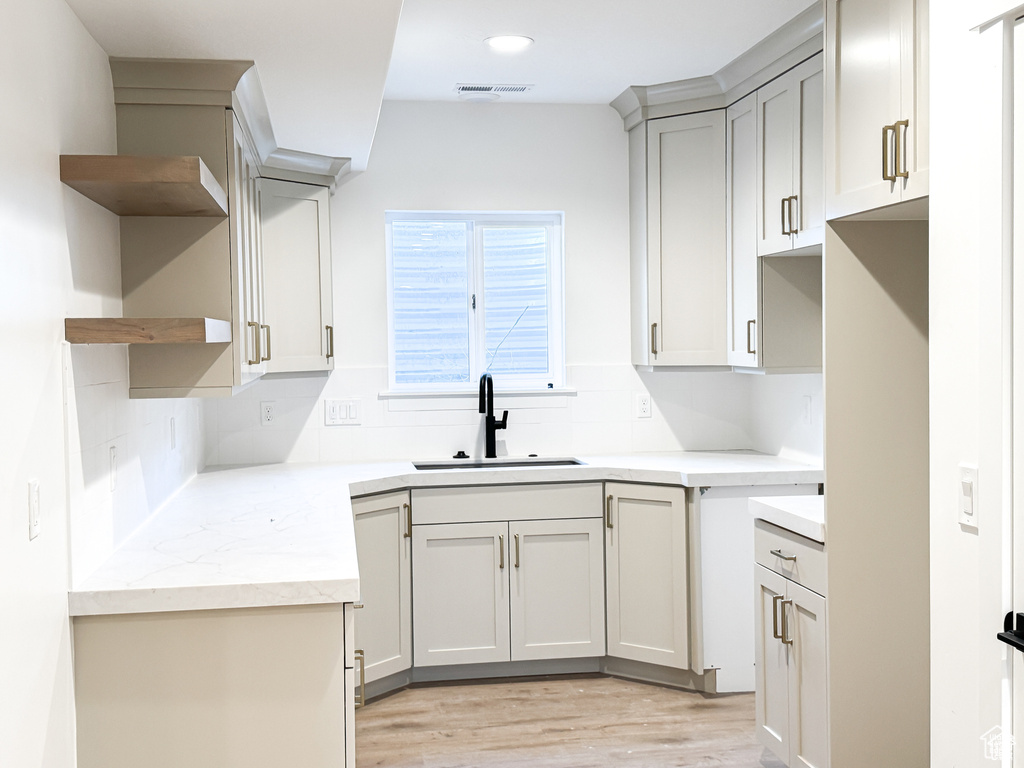 Kitchen with a sink, open shelves, light wood-style floors, decorative backsplash, and recessed lighting